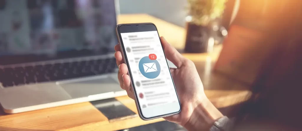 Someone holding up a mobile device with a new email symbol on the screen