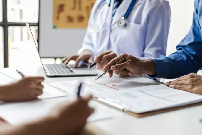 Medical personnel at a table looking at sheets and charts